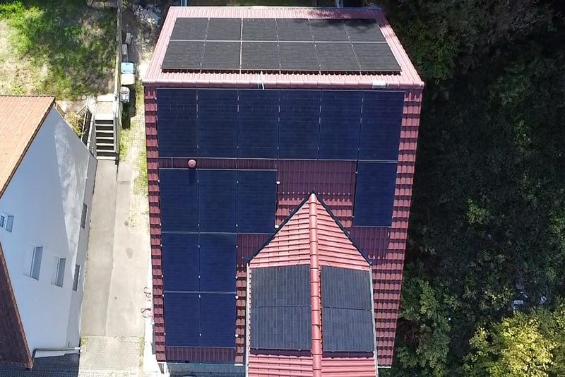 Rotes Ziegeldach mit Zwerchgiebel, schwarze Solarmodule auf allen Fl&auml;chen